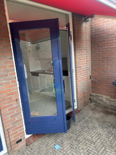 Blauwe deur met glasopening, toegang tot een ruimte met stenen muren.
