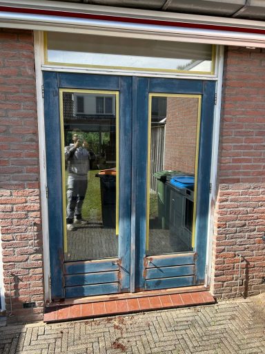Dubbele deuren met gele accenten en weerspiegeling van de omgeving.